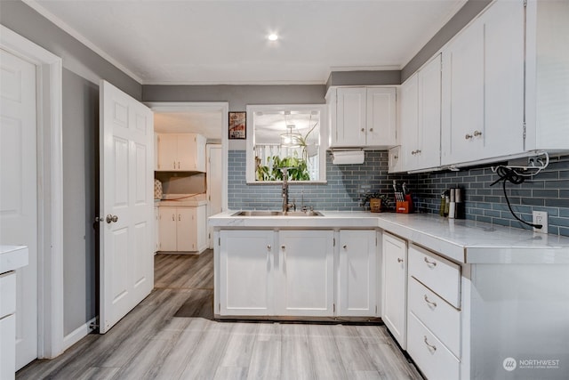 kitchen featuring sink, backsplash, light hardwood / wood-style flooring, and white cabinets