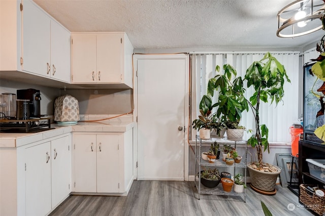 kitchen with white cabinets, a textured ceiling, and light hardwood / wood-style flooring