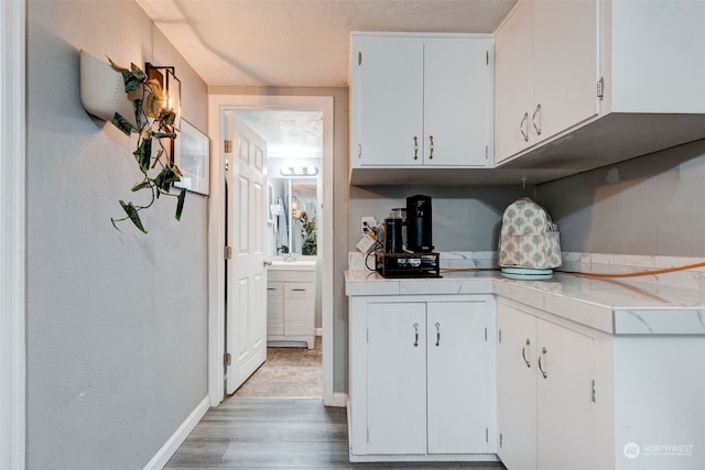 kitchen with hardwood / wood-style floors, a textured ceiling, and white cabinets