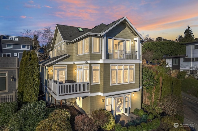 back house at dusk featuring a balcony