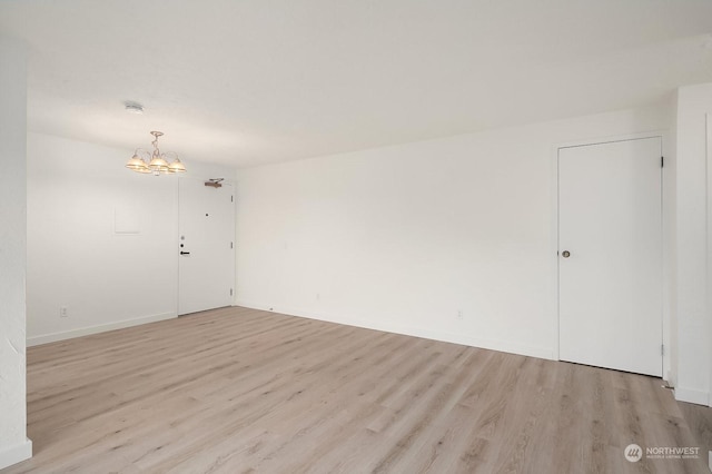 unfurnished room featuring light hardwood / wood-style flooring and a notable chandelier