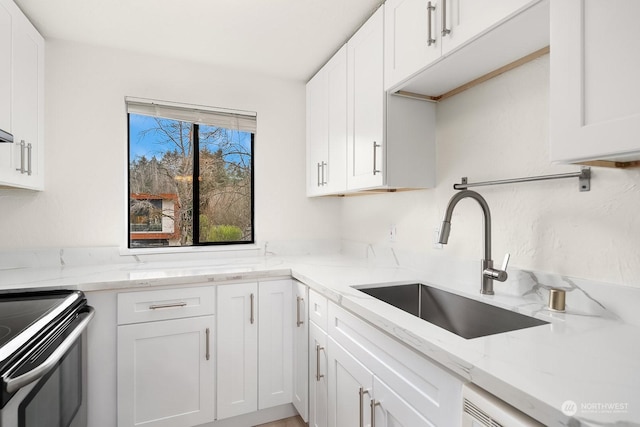 kitchen featuring white cabinetry, sink, light stone counters, and electric stove