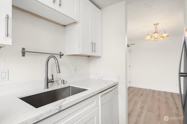 kitchen featuring sink, light stone counters, white cabinetry, dishwasher, and pendant lighting