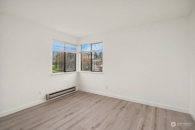 empty room with a baseboard radiator and light hardwood / wood-style flooring