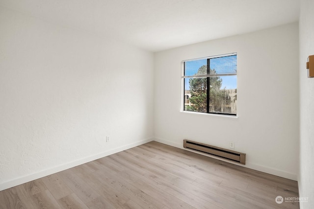 empty room with a baseboard heating unit and light hardwood / wood-style flooring