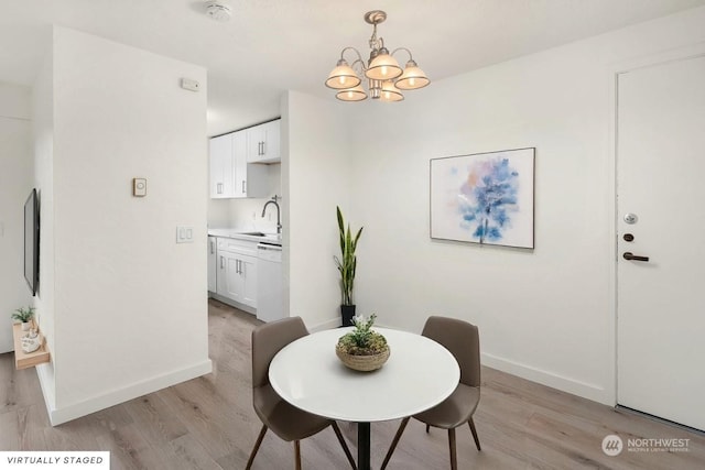 dining area with sink, an inviting chandelier, and light wood-type flooring