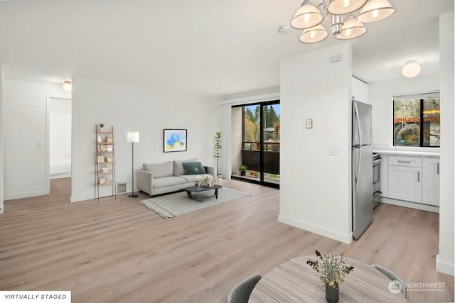 living room featuring an inviting chandelier, plenty of natural light, and light hardwood / wood-style floors