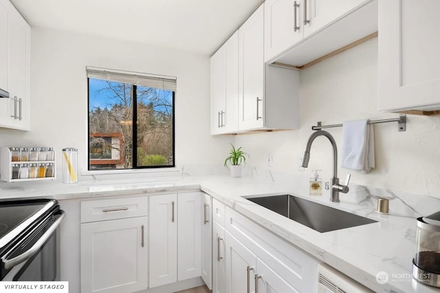 kitchen featuring light stone counters, sink, electric stove, and white cabinets