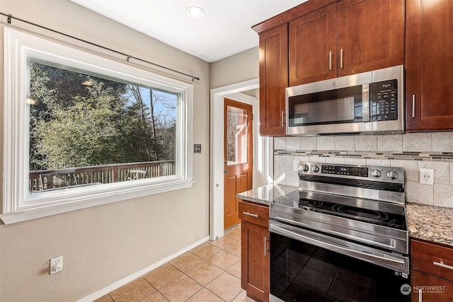 kitchen featuring light stone counters, stainless steel appliances, light tile patterned flooring, and tasteful backsplash