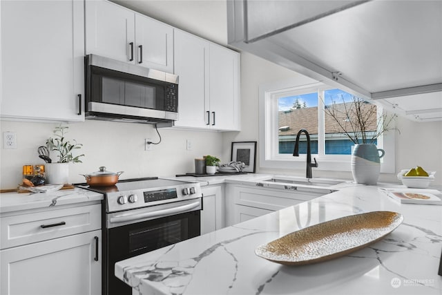 kitchen featuring light stone counters, sink, stainless steel appliances, and white cabinets