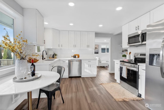 kitchen with stainless steel appliances, plenty of natural light, sink, and white cabinets