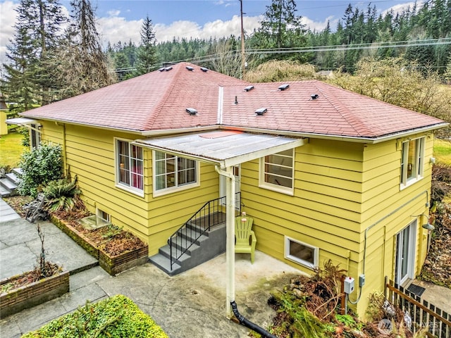 rear view of property featuring roof with shingles