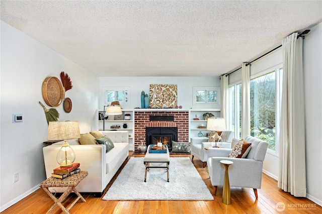 living room with light wood-type flooring, a textured ceiling, and baseboards