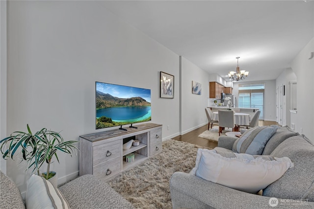 living room featuring baseboards, a notable chandelier, and wood finished floors