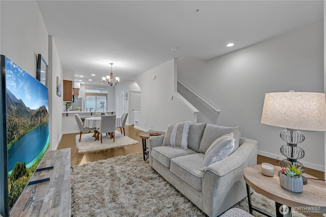 living area featuring recessed lighting, wood finished floors, baseboards, stairway, and an inviting chandelier