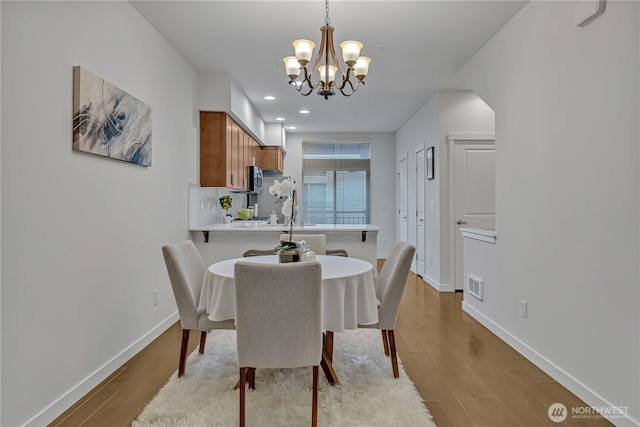 dining room with baseboards, a chandelier, visible vents, and light wood-style floors