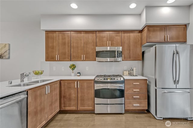 kitchen featuring tasteful backsplash, appliances with stainless steel finishes, light countertops, and a sink