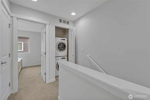 corridor with stacked washer and clothes dryer, recessed lighting, visible vents, light carpet, and baseboards