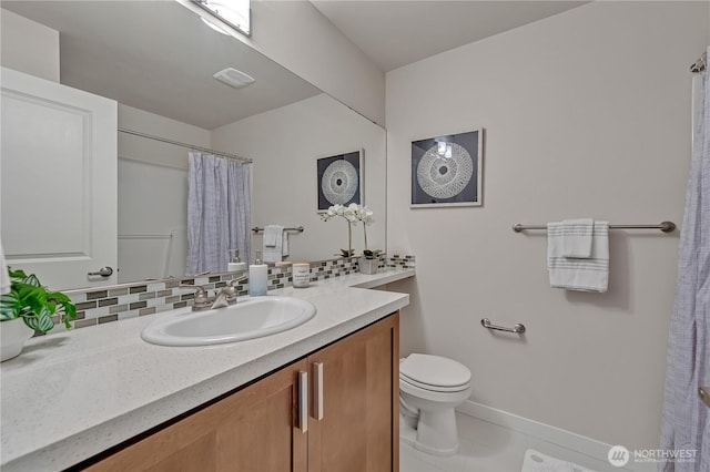 bathroom with toilet, vanity, visible vents, baseboards, and backsplash