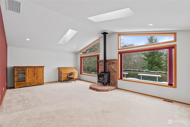 912 Bell Dr, Cosmopolis, WA 98537 - unfurnished living room featuring carpet floors, a wood stove, vaulted ceiling with skylight, and visible vents