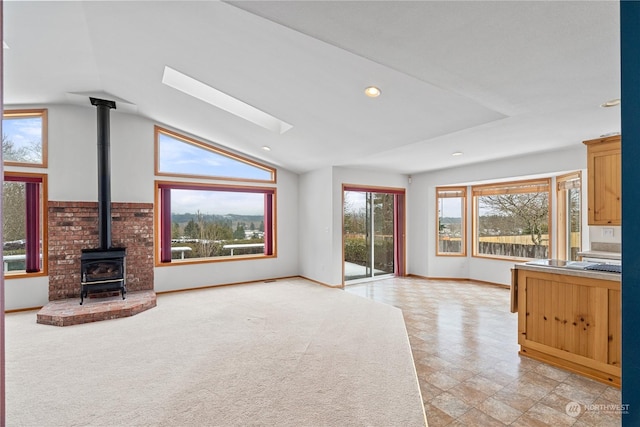 912 Bell Dr, Cosmopolis, WA 98537 - unfurnished living room featuring recessed lighting, a wood stove, light carpet, vaulted ceiling with skylight, and baseboards