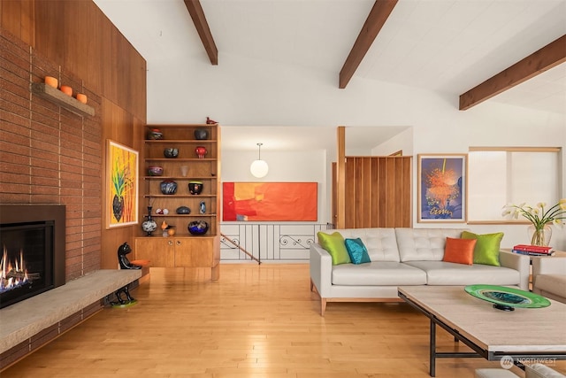 living room with lofted ceiling with beams, a fireplace, and light hardwood / wood-style flooring