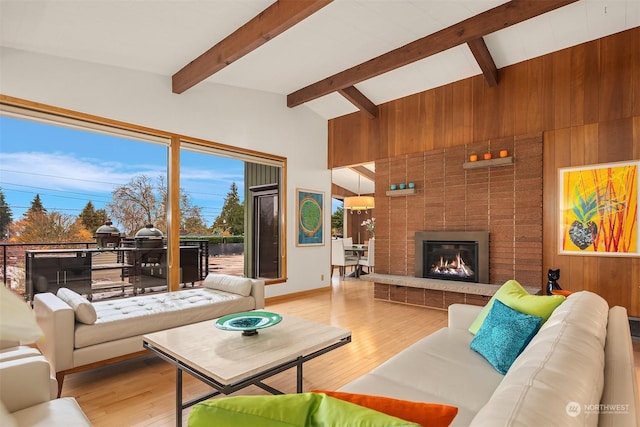 living room with vaulted ceiling with beams, wooden walls, a fireplace, and hardwood / wood-style floors