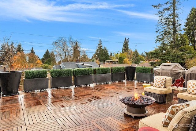 wooden terrace featuring area for grilling and a fire pit