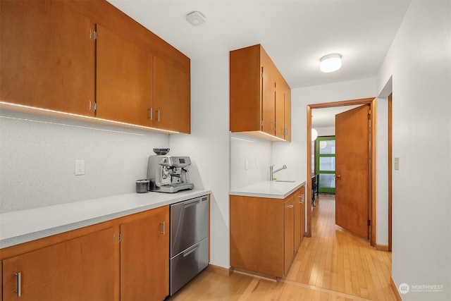 kitchen featuring fridge, sink, backsplash, and light wood-type flooring