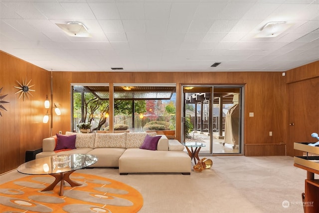 living room with light carpet, a healthy amount of sunlight, and wood walls