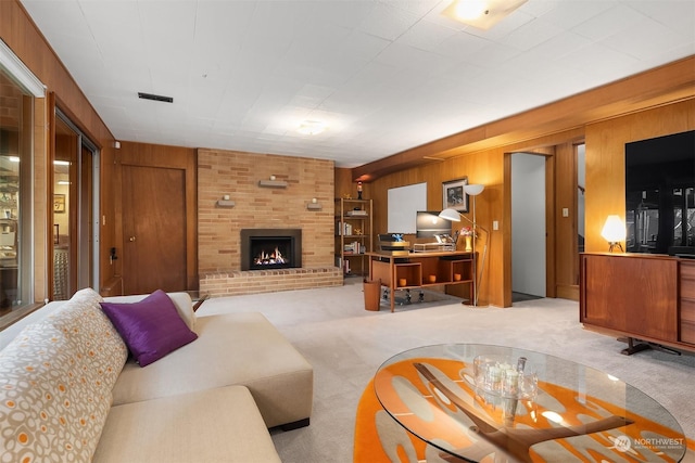 carpeted living room with a brick fireplace and wood walls