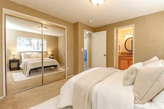 carpeted bedroom with connected bathroom, a textured ceiling, and a closet