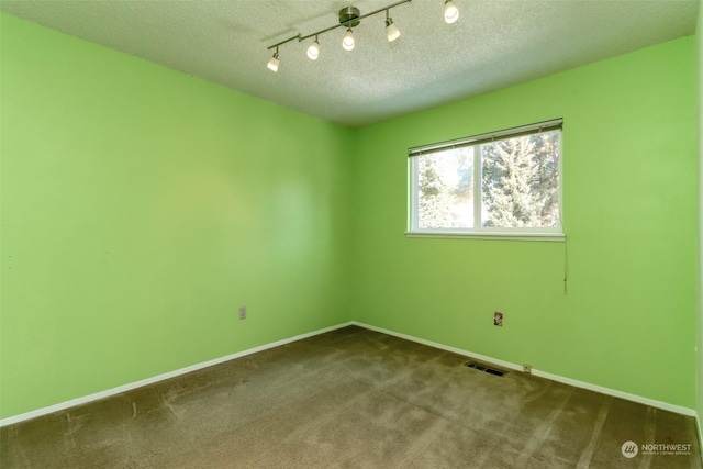 carpeted spare room with track lighting and a textured ceiling