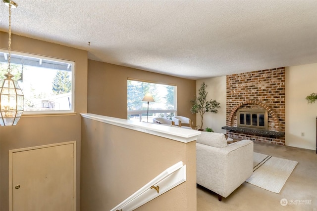 carpeted living room featuring a brick fireplace and a textured ceiling