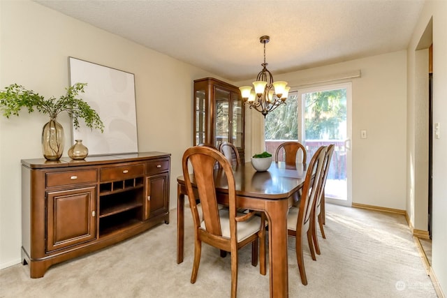 dining area with light carpet, a textured ceiling, and a chandelier