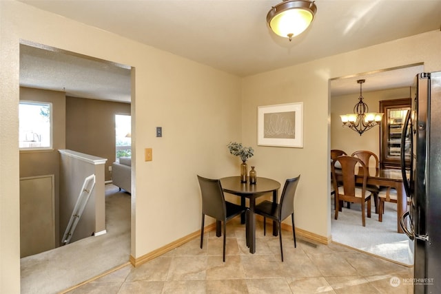 dining space featuring light colored carpet and a notable chandelier