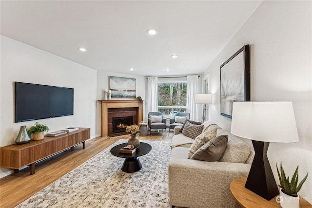 living room featuring a tiled fireplace and light hardwood / wood-style floors