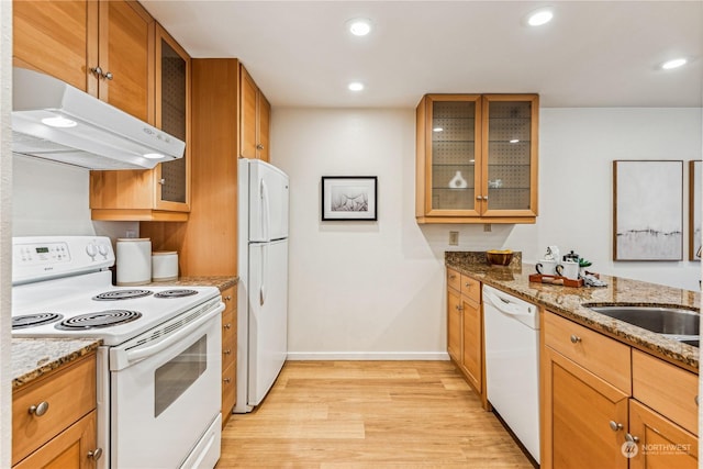 kitchen with light stone counters, white appliances, sink, and light hardwood / wood-style flooring