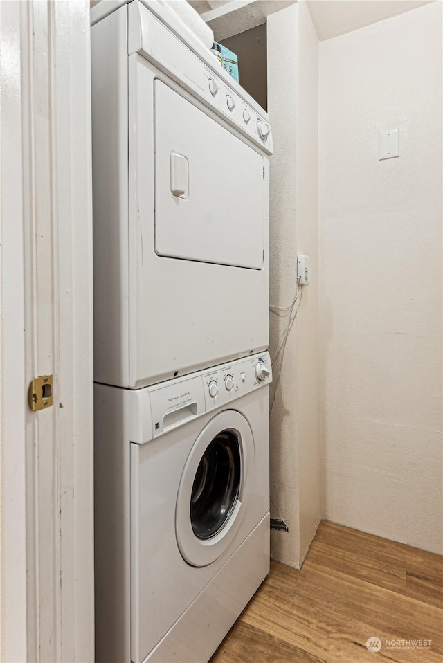 clothes washing area with stacked washer / drying machine and light hardwood / wood-style flooring