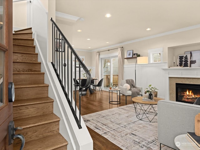 living room featuring ornamental molding, a tiled fireplace, and hardwood / wood-style floors