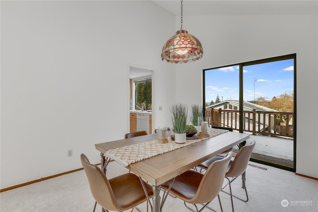 dining space featuring light colored carpet and high vaulted ceiling