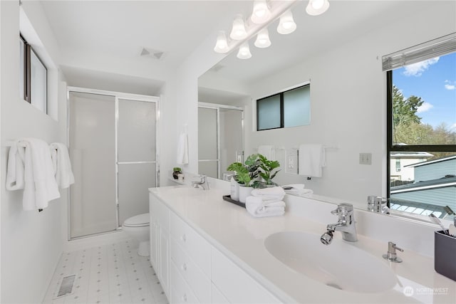 bathroom with toilet, vanity, and a shower with shower door