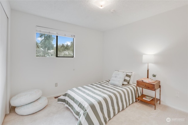 bedroom featuring light colored carpet and a textured ceiling