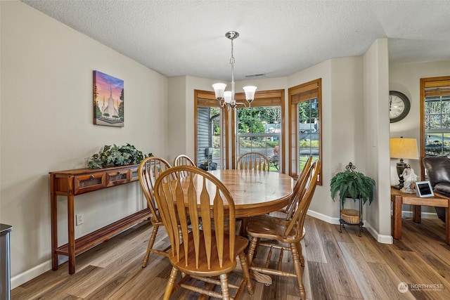 dining area featuring plenty of natural light, a textured ceiling, wood-type flooring, and a notable chandelier