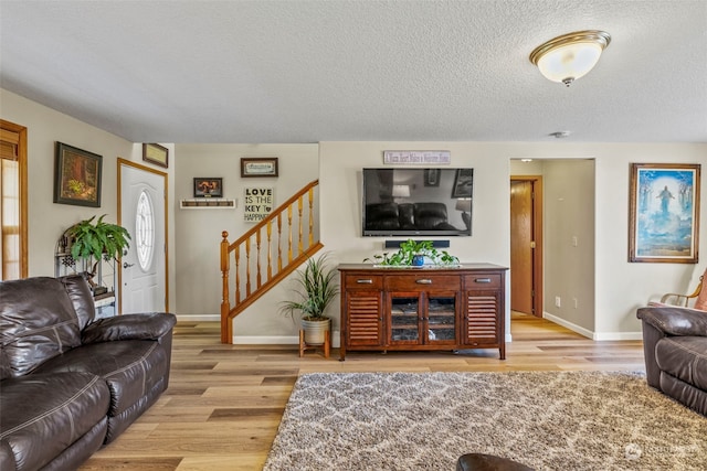 living room with a textured ceiling and light wood-type flooring