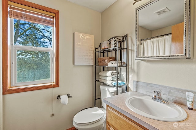 bathroom featuring tasteful backsplash, vanity, and toilet