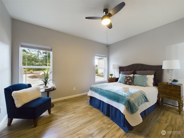 bedroom with ceiling fan, multiple windows, and light wood-type flooring