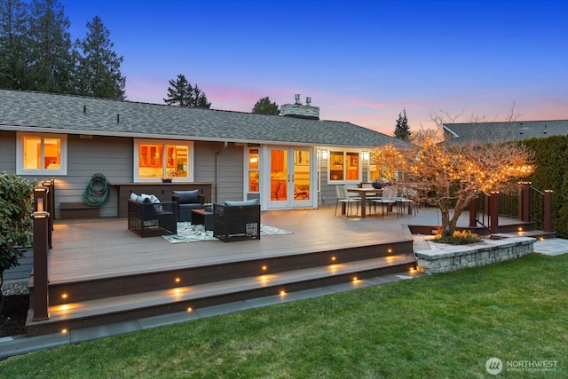 back of house at dusk featuring a yard, roof with shingles, outdoor lounge area, and a wooden deck