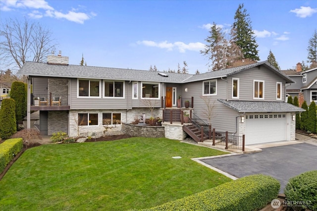 split foyer home featuring a garage, a front yard, driveway, and a chimney