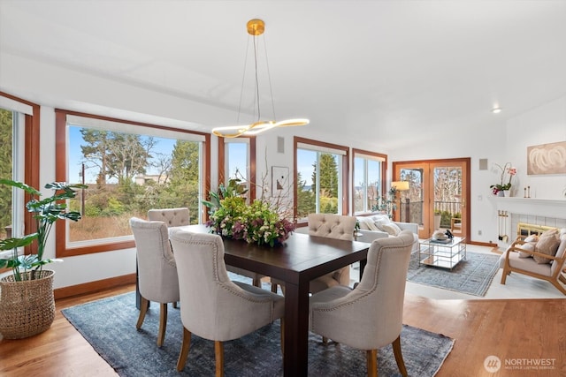 dining area featuring baseboards, a tiled fireplace, and wood finished floors